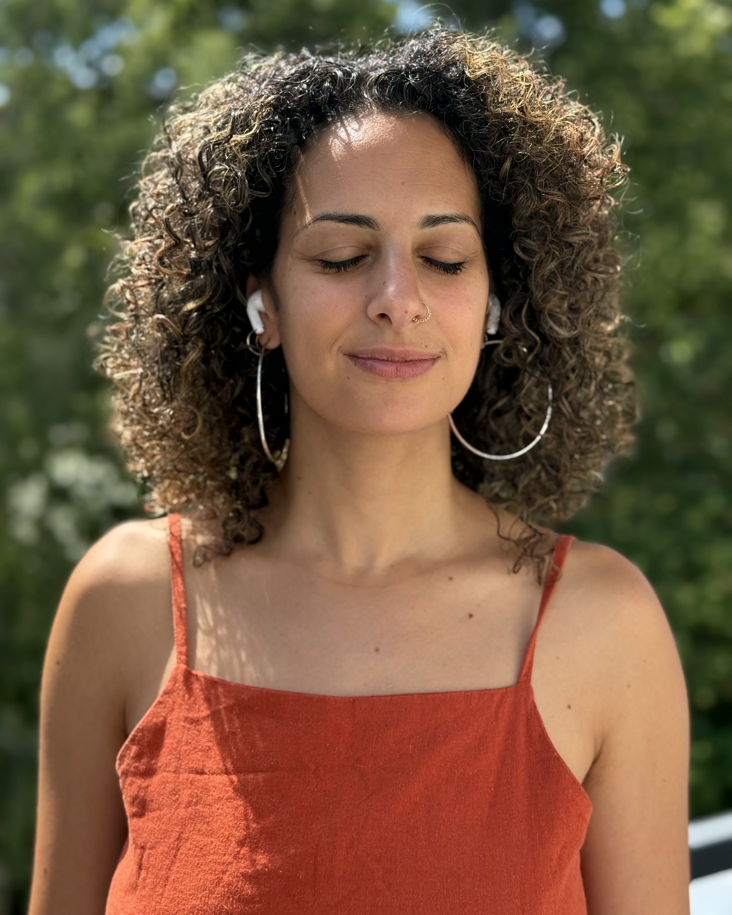 A woman with earphones, eyes closed in a calm SYLO moment